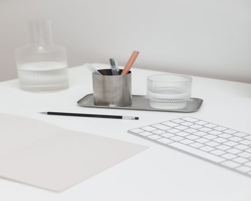 A glass of water on a modern desk next to a notebook
