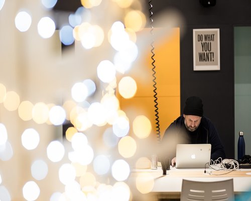 Person adjusting laptop screen brightness in a coworking space