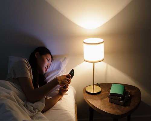 Woman reading on her smartphone with a warm night light